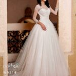 Bride in a long white wedding gown, standing gracefully at the entrance of a beautiful building and striking a pose