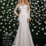 A girl in an ivory white long gown, posing in front of a wall full of white flowers and green plants