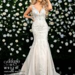 Bride in an ivory white long gown, posing in front of a wall decorated with white flowers and green plants