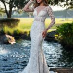 Bride in an ivory white long gown, posing in front of a water pool surrounded by trees