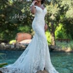 Bride in an ivory white long gown, posing in front of a water pool surrounded by trees