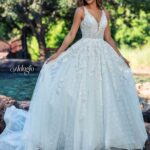 Bride in an ivory white long gown, posing in front of a water pool surrounded by trees