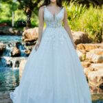 Bride in an ivory white long gown, posing in front of a water pool surrounded by trees